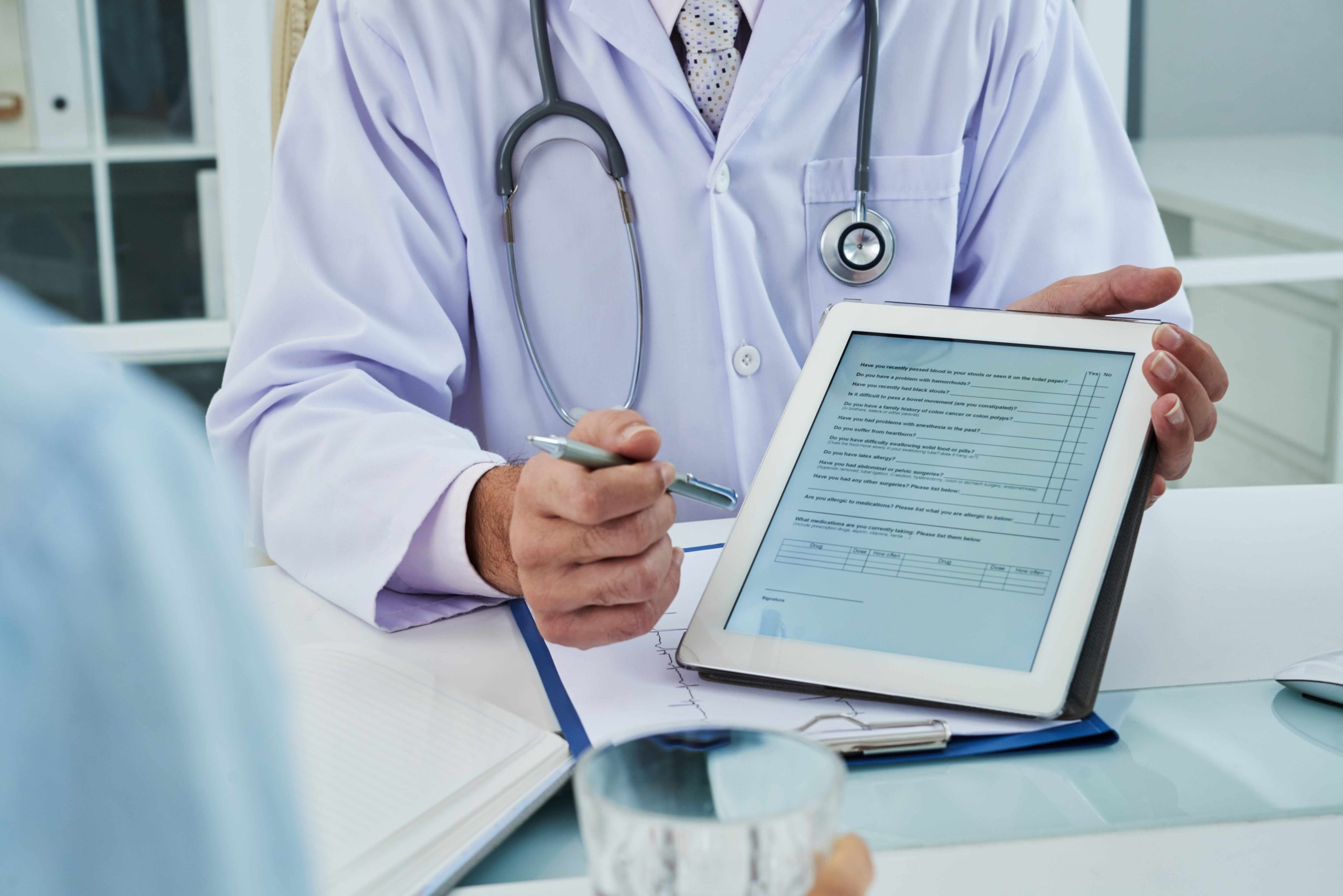 unrecognizable doctor extending digital tab anonymous patient fill questionnaire.jpg scaled